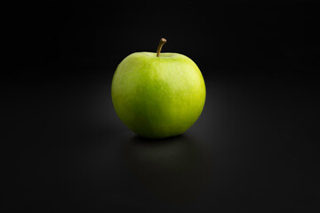Green apple on a black background close up