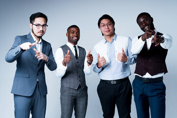 Group of african american and asian businessmen in suits point fingers to the camera and thumbs up