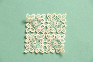 knitted white lace doily lies on a colored paper background - obrazy, fototapety, plakaty