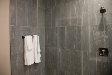 bathroom towels hanging on rail in grey tiled shower room
