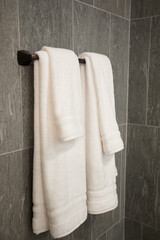 bathroom towels hanging on rail in shower room with grey tile walls
