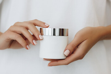 Woman hands with cream container with blank label