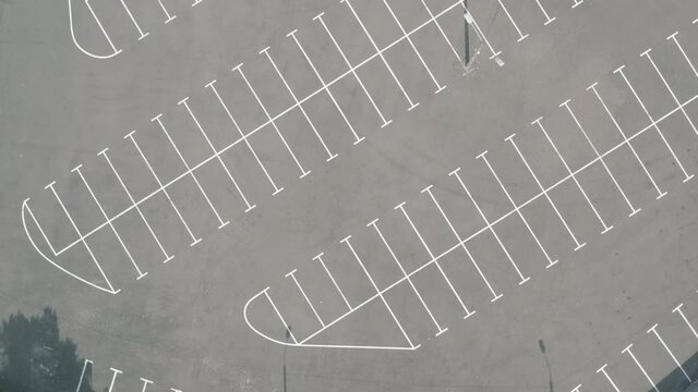 top shot large empty parking lot. dry asphalt sunny day. cinematic camera movement around an empty ground parking lot. white line markings on wet asphalt. 4k footage