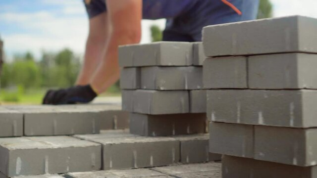 A worker lays a stack of bricks or paving slabs, for better transfer to the place of work or transportation.. He folds a stack on a sunny summer day.