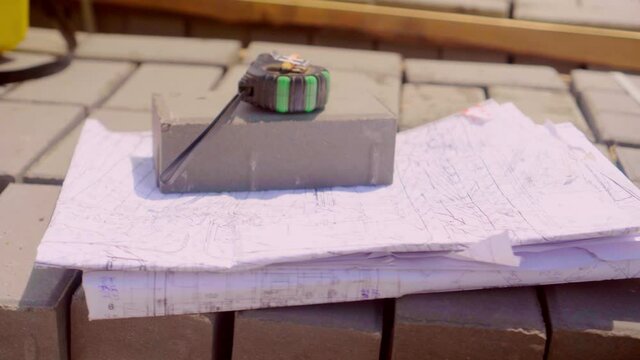 Blueprints - rolls of architectural drawings, roulette, yardstick - folding ruler and drawing of the golden section smoothly rotate on the surface of the architectural drawings