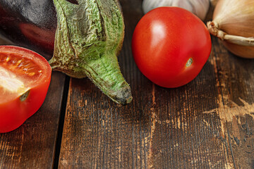 vegetables for the eggplant saute: eggplant, tomatoes, onions and garlic on a wooden table