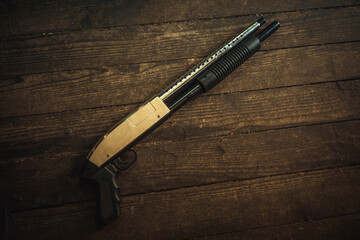 A black Winchester shotgun on the wooden floor of the house.Weapon