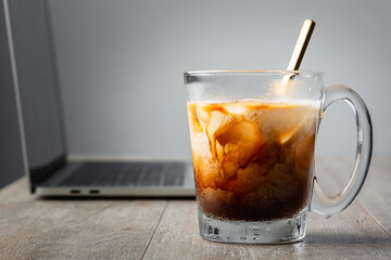 Iced latte coffee in glass on work table with computer and white background