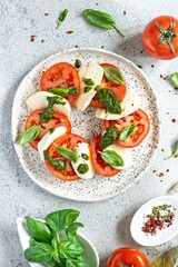 Caprese salad with juicy tomatoes, fresh mozzarella and pesto. Concept for a tasty and healthy appetizer, flat lay. Italian food, cuisine.