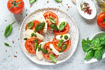 Caprese salad with juicy tomatoes, fresh mozzarella and pesto. Concept for a tasty and healthy appetizer, flat lay. Italian food, cuisine.