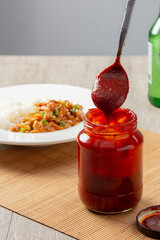 Gochujang (Korean spicy sauce) in jar and dipping by spoon