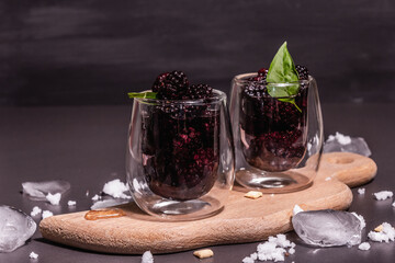 Refreshing blackberry fruit drink with ice on a wooden stand