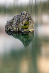 Long esposure of a rock in the lake of mountain pass Julierpass in Switzerland