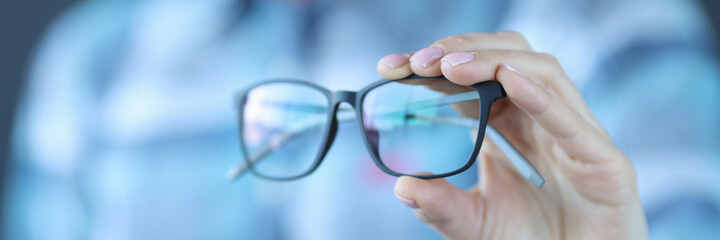 Glasses with black optics are held in hand