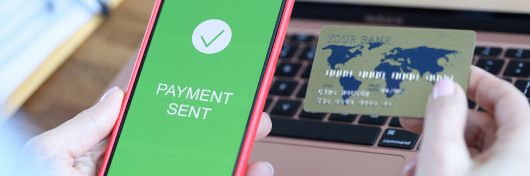 On smartphone screen, inscription payment is sent in hand of bank payment card