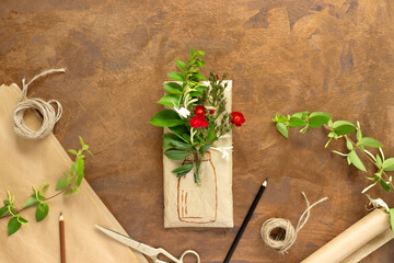 Gift wrapped in wrapping paper with bouquet of crimson roses and painted vase. Rolls of vintage packing paper, honeysuckle branches for decoration.