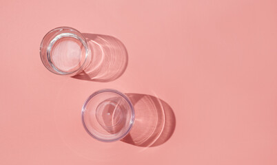 Empty glasses on pink pastel background, top view