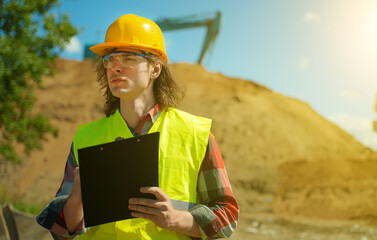 Builder with documents on the background of a road junction construction site.