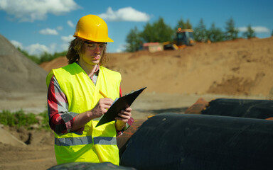 Building contractor counting number of pipes on the construction site.