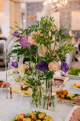 Flower bouquets in transparent vases on guest tables, room decor, fresh flowers