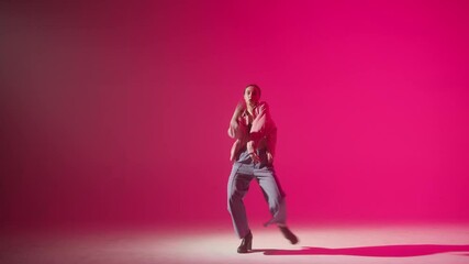 Young woman wearing high heels dancing contemporary on pink neon background in studio. Shooting of modern slow dance choreography. Motion of female dancer showing dance movings. 