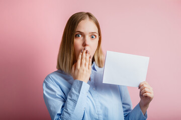 Emotional portrait of surprised young woman show empty mockup copy space white card. Blonde woman...
