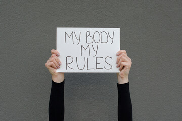 Female hands holding a protest sign with the claim My Body My Rules. Right on accepting individual...