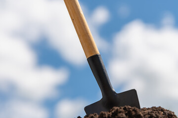 A shovel stuck in the ground against the sky.