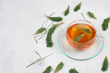 Pine needle tea in a cup on a white textured background, empty copy space for text