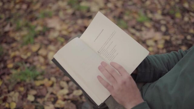 Man looking through a book in a park