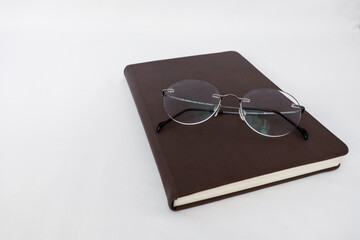 notebook and glasses on a white background. the concept of development through reading and learning.