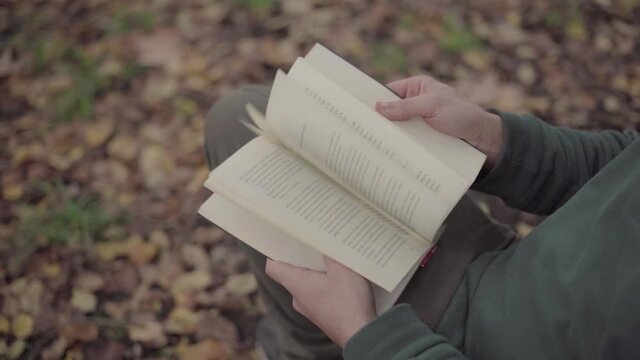 Man looking through a book in a park