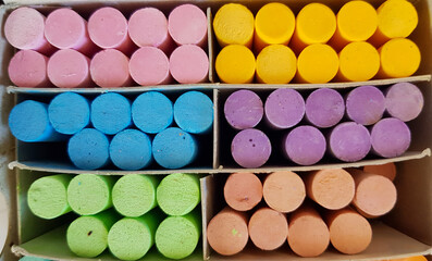 Different colored chalks are neatly arranged in a box.