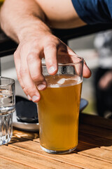 A man holds a glass of beer in the bar
