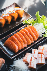 Salmon Sashimi in Japanese buffet restaurant menu.Fresh salmon fillet on black plate salmon slices.Asian people eating sashimi set Japan restaurant.salmon sashimi.Asian Food Menu.seafood sashimi.