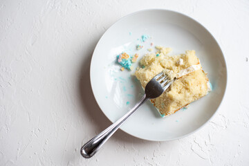 Half-eaten slice of cake with fork on white plate and background.
