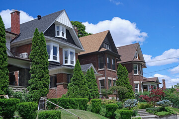 Residential street with row of older urban three story brick houses with rooms under the gables