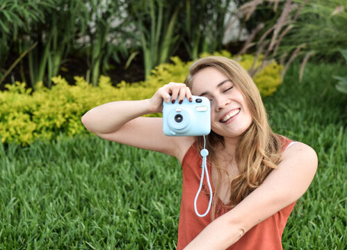 Retrato de una mujer joven utilizando una camara instantanea para tomar una fotografia, guatemalteca, rubia, muy bonita, latina
