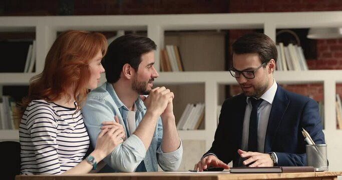 Happy young married caucasian family couple making agreement with professional real estate agent or broker, shaking hands, celebrating purchasing own house, feeling excited taking keys at meeting.