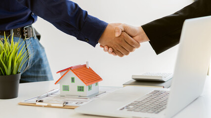 The sales representative shakes the customer's hand and offers a home purchase contract to purchase the current home and lease. Sales agents offer house projects, ideas to buy and rent.