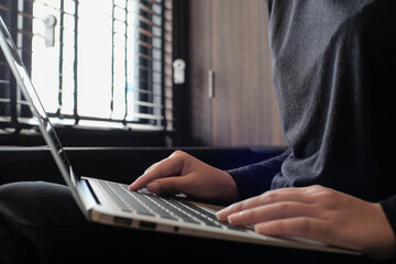 Working by using a laptop computer on wooden table. Hands typing on a keyboard.