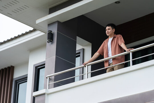 happy man relaxing and looking from balcony of home