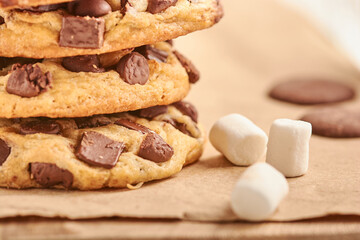 GALLETAS EN PILA CON CHIP DE CHOCOLATE Y MASMELLOS EN UNA TABLA CON PAPEL CAFE