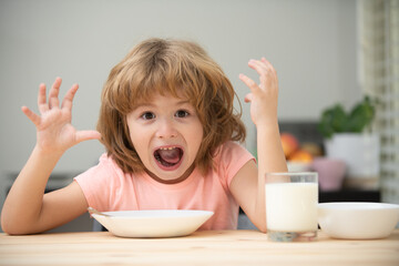 Funny kid with plate of soup. Child dinner. Best breakfast ever. Portrait of fun kid having healthy tasty snack. Small kid crazy posing by kitchen table.