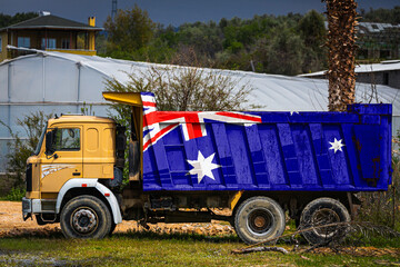 Dump truck with the image of the national flag of Australia is parked against the background of the countryside. The concept of export-import, transportation, national delivery of goods