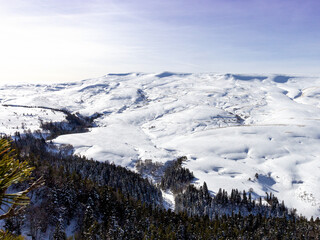 Winter, panoramic views of snow-capped mountains and alpine glades in the bright sun.