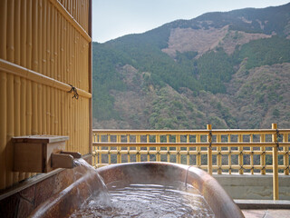 Japanese traditional open air private onsen bathtub with  autumn view with mountains and forest