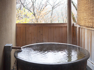 Japanese traditional open air private onsen ceramic bath tub with autumn forest view 