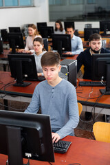 Fototapeta premium Portrait of female and male students working on computers in classroom