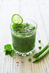 Cucumber cilantro parsley celery smoothie on white wooden background
